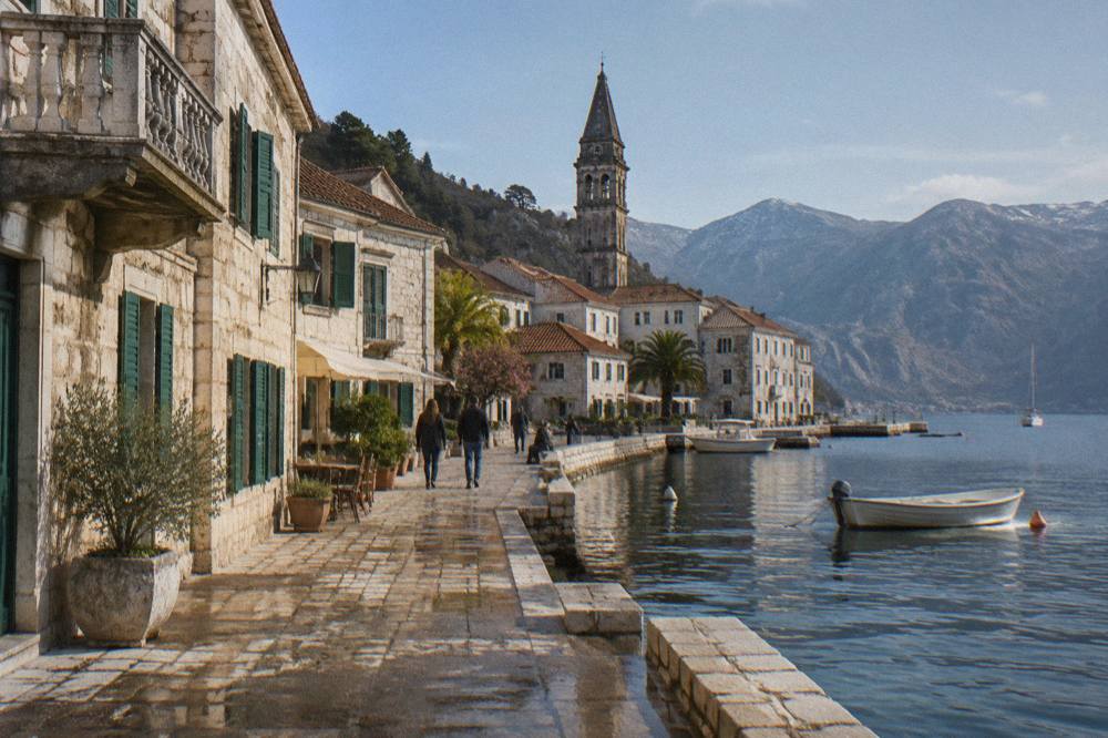 Perast waterfront stone palaces along a calm bay at morning with church towers behind